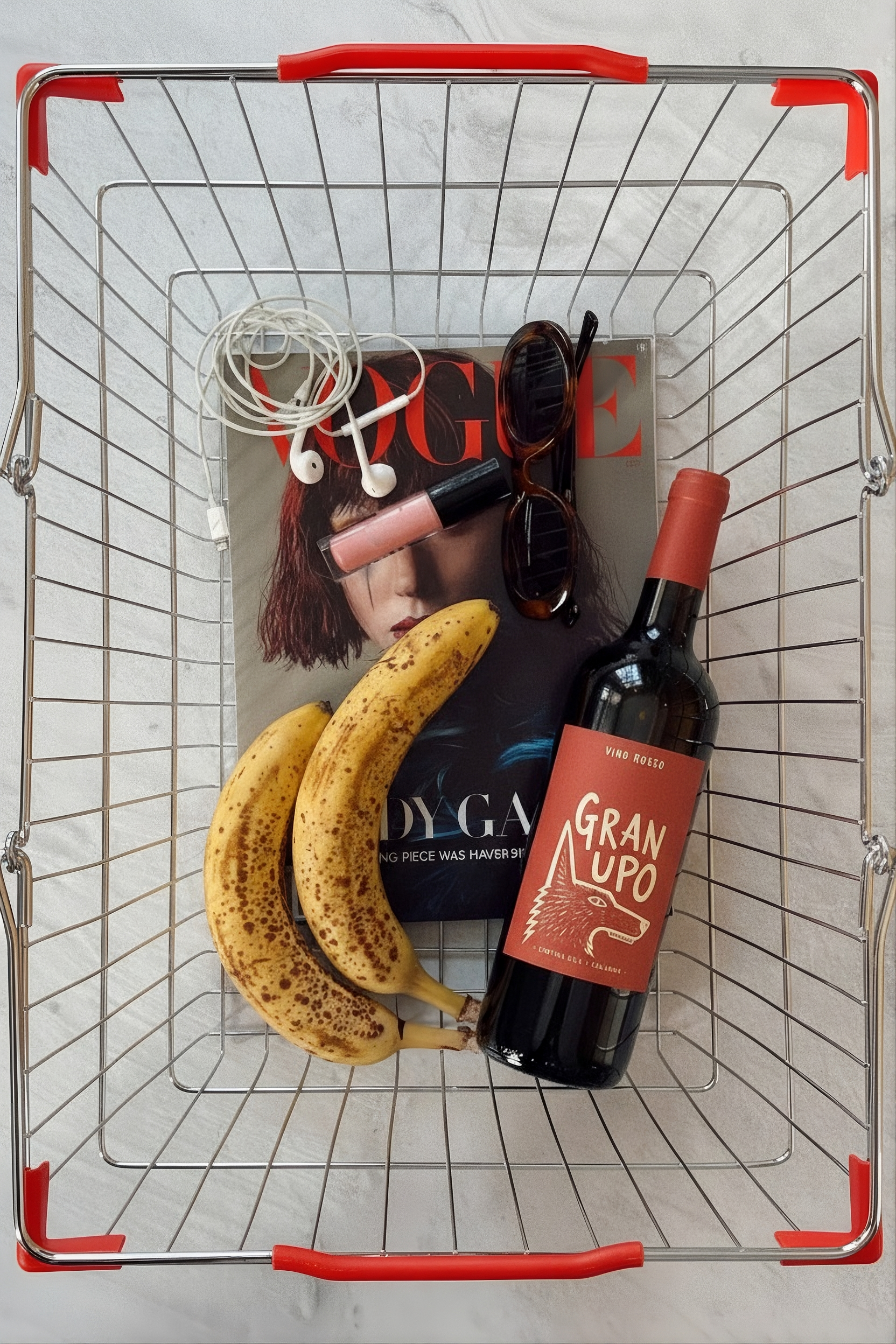 Bottle of wine in a shopping basket with a vogue magazine and some bananas.